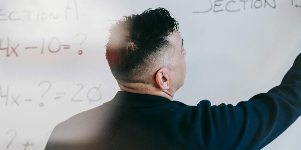 A professional explaining a complex system design on a whiteboard, demonstrating problem-solving and architectural thinking during an interview.