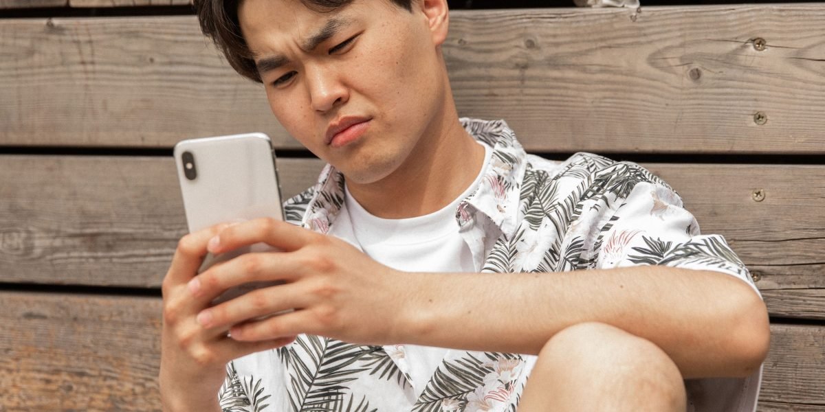 A person looking at their phone with a skeptical expression, reflecting developer sentiment towards inauthentic brand marketing.