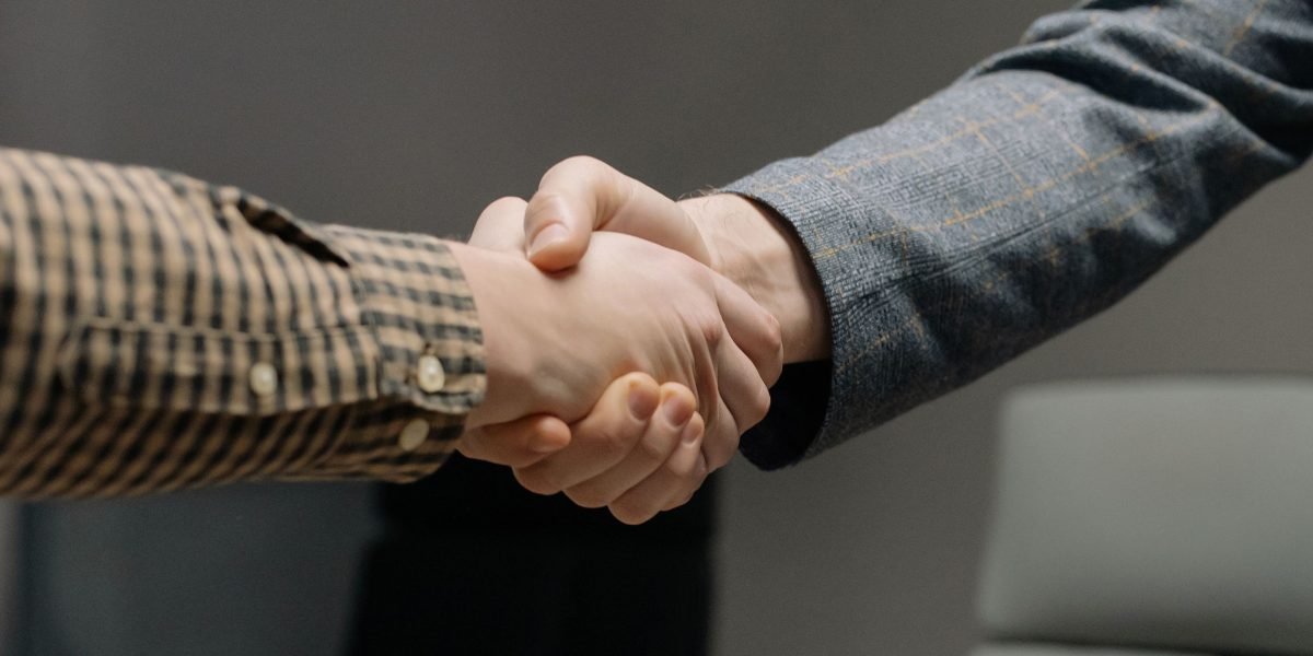 Professionals shake hands in a moment of agreement or celebration, symbolizing career success.
