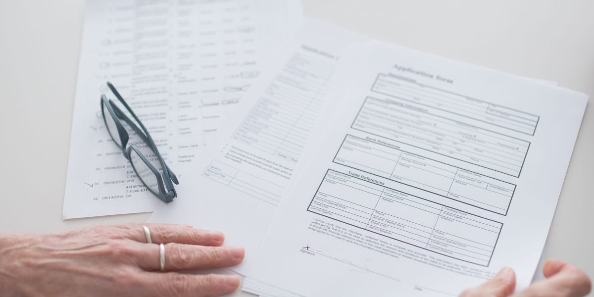 A person focused on carefully reviewing documents, perhaps a resume or application, before submission.