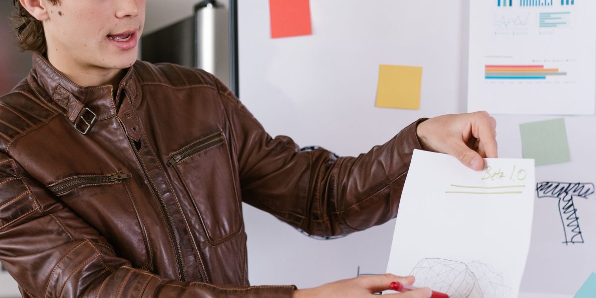 An individual confidently presenting and explaining complex concepts to a team using a whiteboard.