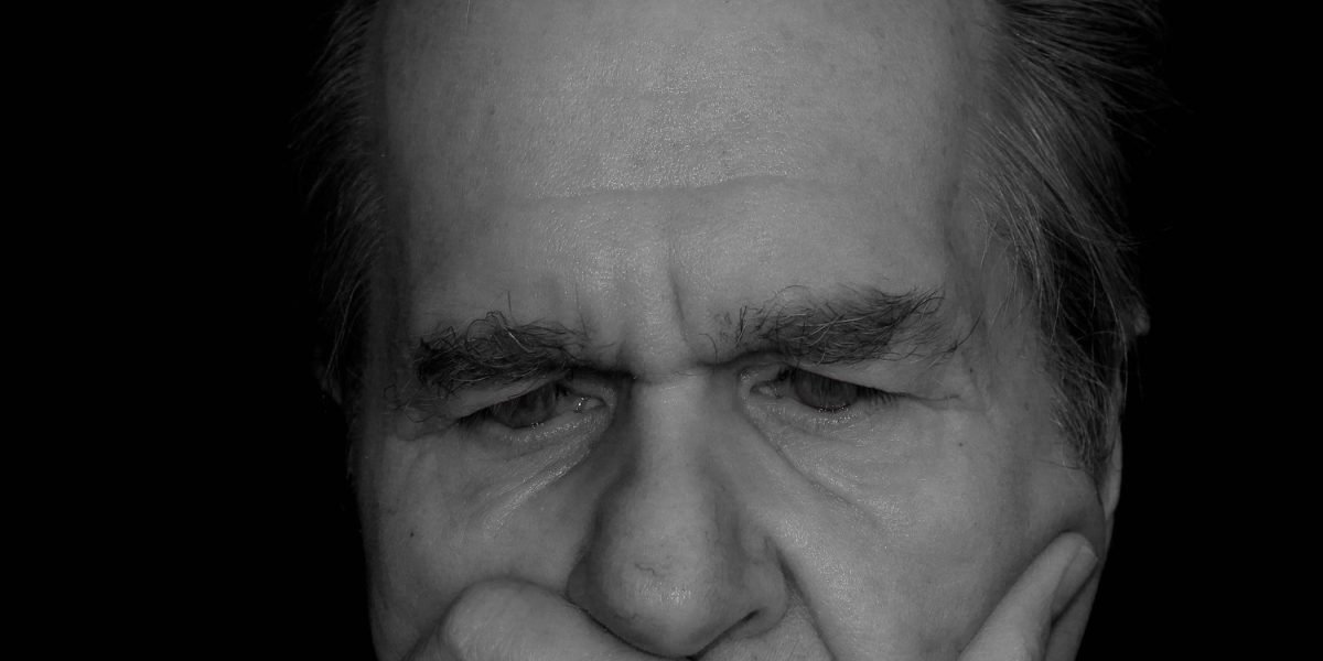 A person looks contemplative, symbolizing the deep thought and careful consideration required for AI security and compliance in beta programs.